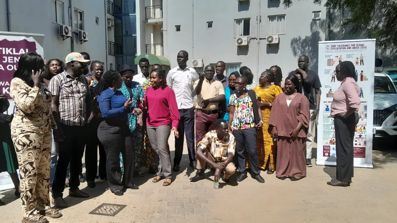 Workshop participants gathered outside Landmark Hotel in Juba, beside a "Zero Tolerance for Sexual Exploitation and Abuse" banner.